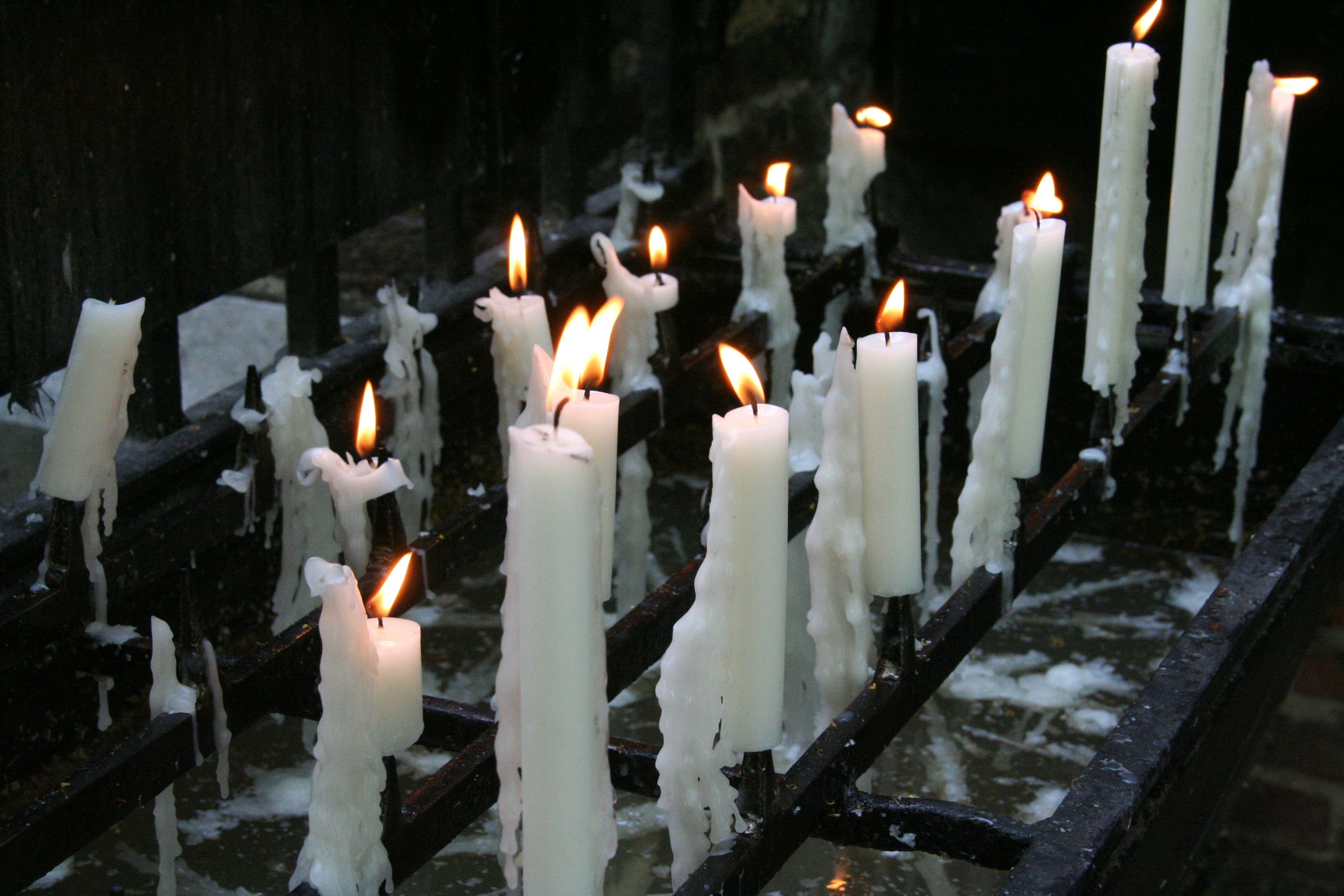A multi-row black metal altar with white burning candles